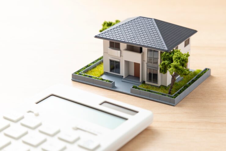 住宅模型と電卓。建築費用のイメージ