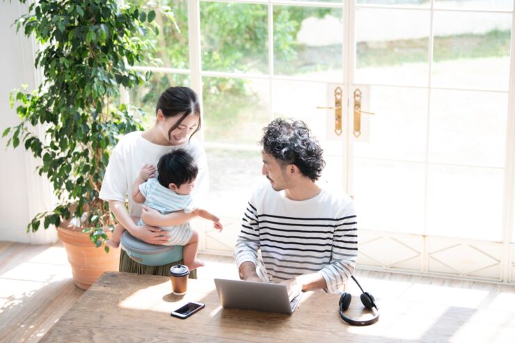 自宅でリモートワークしながら家族と会話する男性