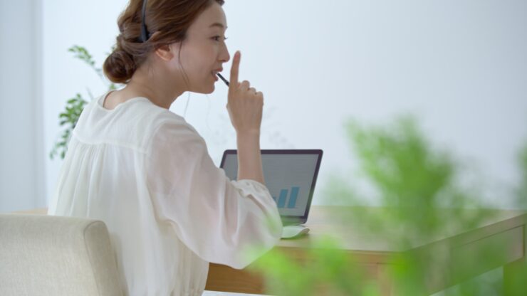 周りに注意しながら自宅でリモートワークする女性