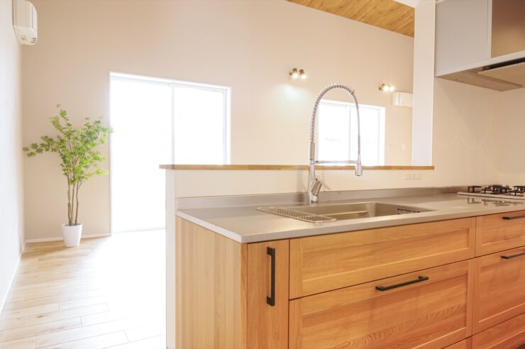 木目柄のI型対面キッチンからリビングダイニングを見た様子