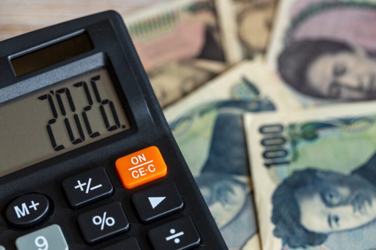 2026と打ち込まれた黒い電卓、背景にお札