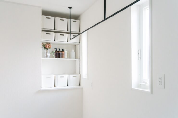 白い壁紙と黒いアイアンの物干しがスタイリッシュなランドリールーム