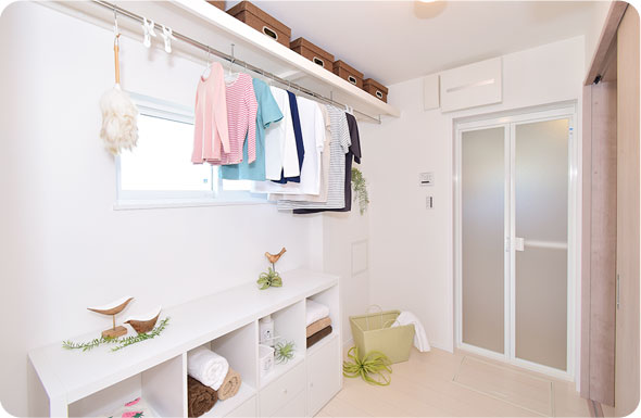ハンガーラックと背の低い収納を備えた、脱衣所兼用のランドリールーム