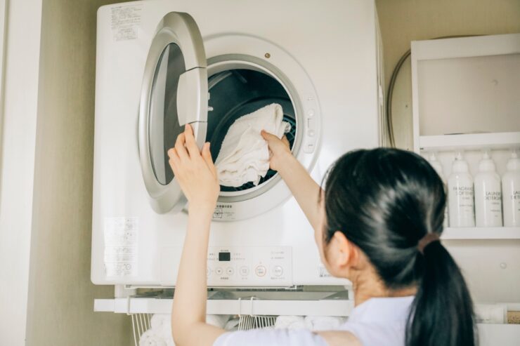 衣類乾燥機に洗濯物を入れる女性