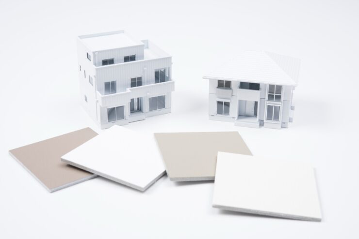 2つの真っ白な住宅模型と外壁材のサンプル