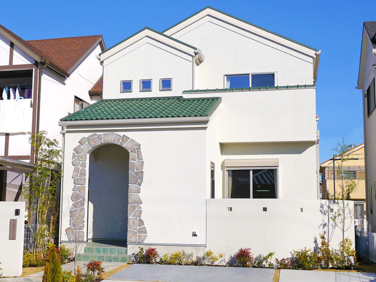 屋根の緑と玄関の石目調のデザインが特徴的なプロヴァンス風の住宅外観