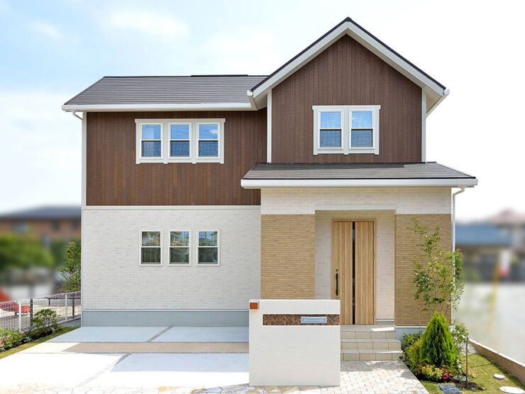 上部を木目調、下部をアイボリーとベージュで仕上げた住宅外観