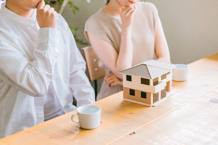 住宅模型の前で悩む若い夫婦