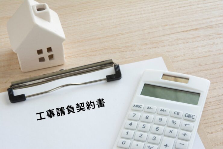 工事請負契約書と電卓、住宅型のブロック