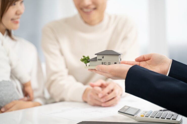 家の模型を持って設計の話をする担当者