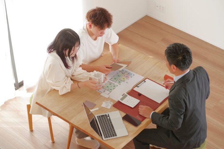 営業マンと家づくりの相談をする若い夫婦